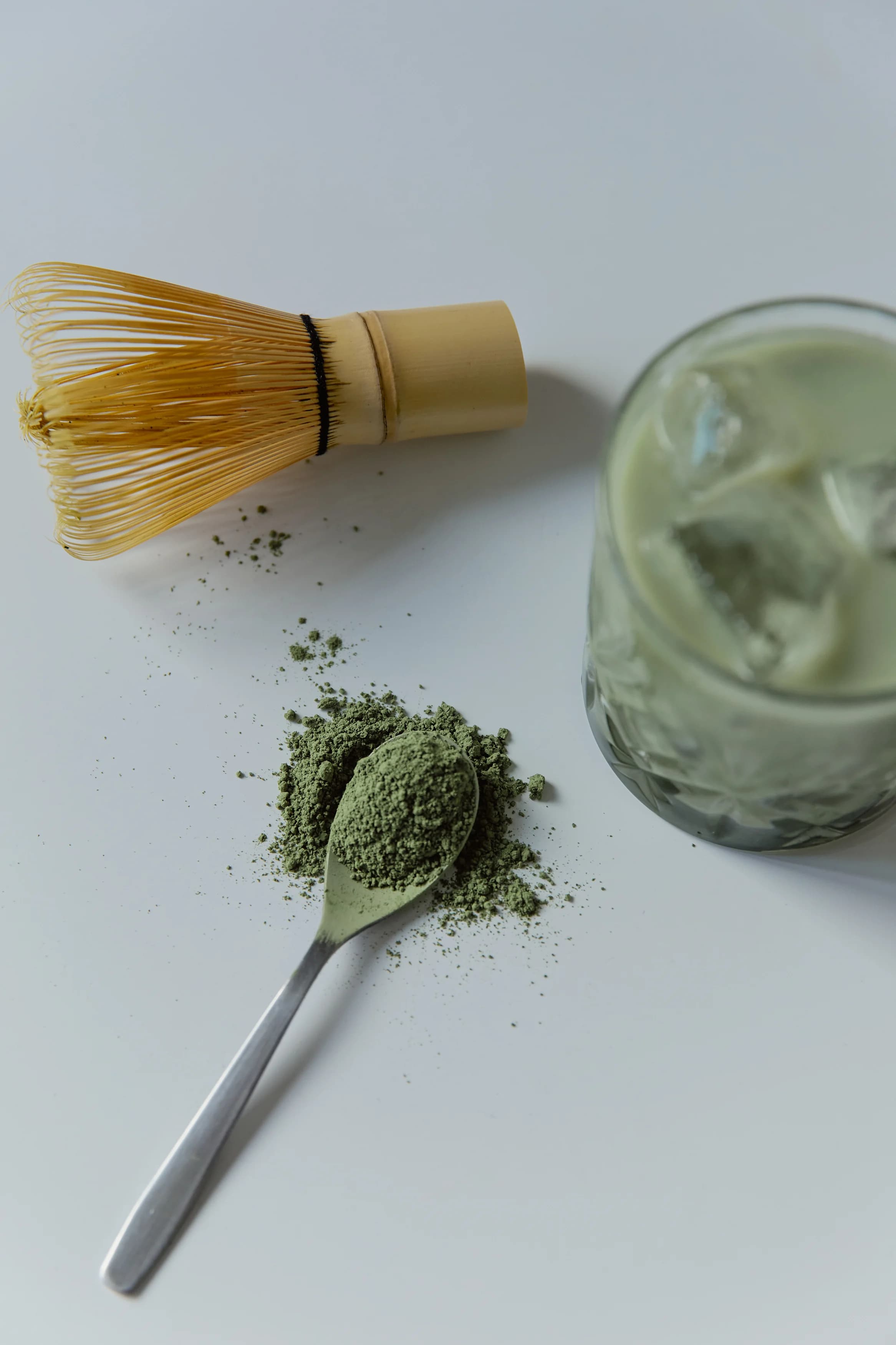 Matcha powder with bamboo whisk and iced matcha drink